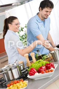 Smiling couple cooking in modern kitchen Stock Photos