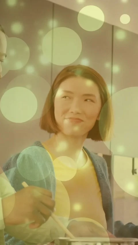 Smiling couple cooking together in kitchen with glowing bubbles animation over Vídeo Stock 343824503