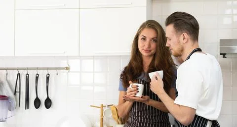 Smiling couple drinking coffee in kitchen and spending time together Stock Photos