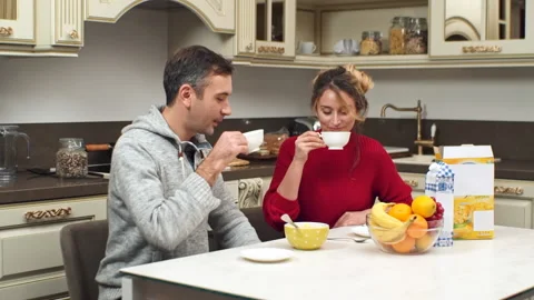 A smiling couple drinking tea and talking on a kitchen. Looking at each other. Stock Footage 145141824