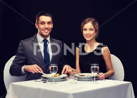 Smiling couple eating main course at restaurant Stock Photos
