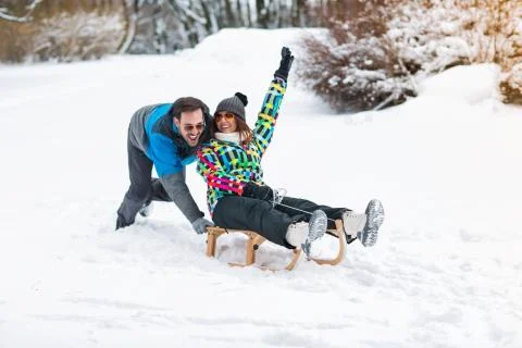 Smiling couple having fun on winter day and using sleigh Stock Photos
