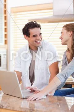 Smiling couple with laptop in the kitchen Stock Photos