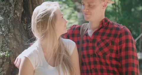 Smiling couple looking at camera while standing by the lake in woods. 動画素材 79928792