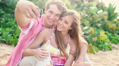Smiling couple in love taking self portrait with camera phone on beach Stock Footage 58162554
