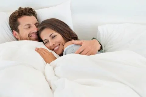 Smiling couple lying on the bed Stock Photos