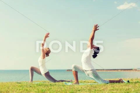 Smiling couple making yoga exercises outdoors Stock Photos