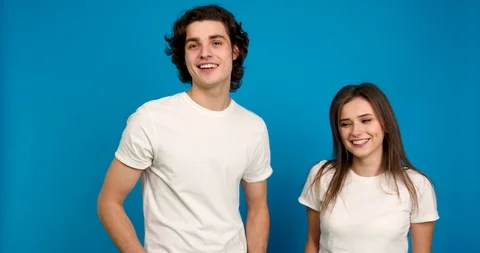Smiling couple posing together, embracing and showing thumb up isolated on blue 스톡 동영상 124904410