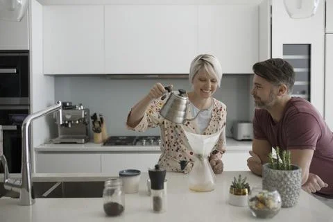 Smiling couple preparing pour over coffee in morning kitchen Fotos Stock