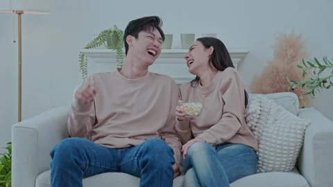 Smiling couple relaxing while watching TV in the living room Stock Footage 305224959