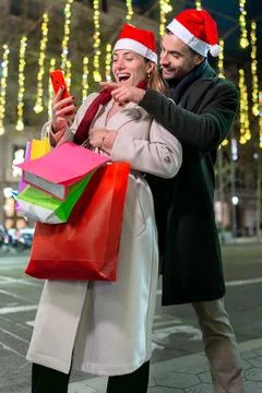 Smiling couple in Santa hats taking a selfie while Christmas shopping.Vertical Stock Photos