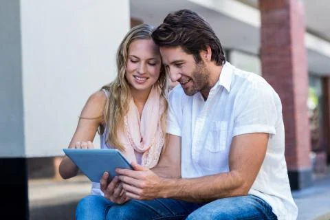 Smiling couple sitting and using tablet computer together Stock Photos
