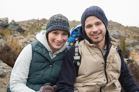 Smiling couple sitting on rock while on a hike Foto stock