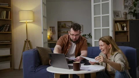 Smiling Couple Sorting Documents and Managing Finances using Laptop Stock Footage 327683728