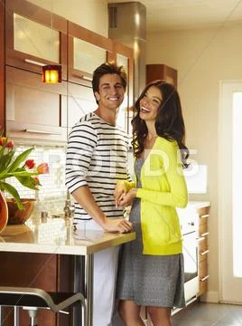 Smiling couple standing together in kitchen Stock Photos