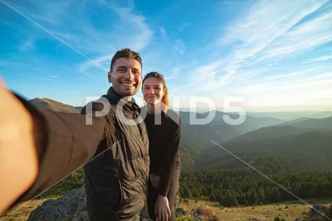 The smiling couple taking a selfie on the mountain background Stock Photos