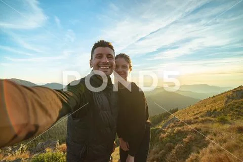 The smiling couple taking a selfie on the mountain background Stock Photos