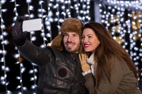 Smiling couple taking selfie with smart phone at ice rink Stock Photos
