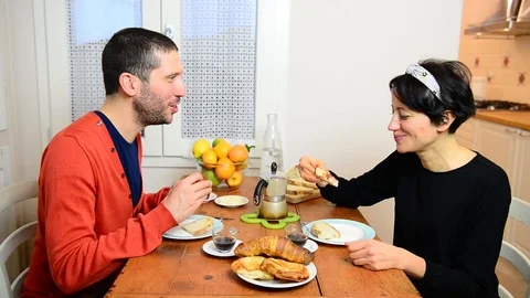 Smiling couple talks while eats bread and drinks coffee for healthy breakfast 스톡 동영상 122293222