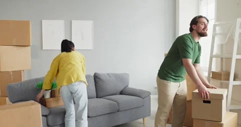 Smiling couple unpacking boxes in new apartment, arranging home interior Stock Footage 338129085