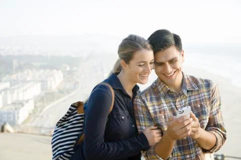 Smiling couple using cell phone outdoors Photos