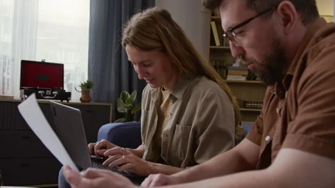 Smiling Couple using Laptop Managing Finances and Sorting Documents Stock Footage 327682492