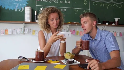 Smiling Couple Using Mobile Phone in Coffee Shop Видео 70722346
