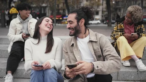 Smiling couple using smartphone and laughing outdoors. People and technology Stock Footage 219724467