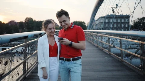 Smiling couple using smartphone on bridge in city smile attractive beautiful Stock Footage 95450048