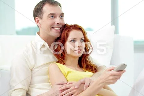 Smiling couple watching TV together at home Stock Photos