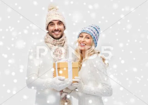 Smiling couple in winter clothes with gift box Stock Photos