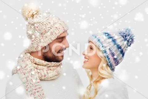 Smiling couple in winter clothes hugging over snow Stock Photos