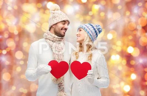 Smiling couple in winter clothes with red hearts Stock Photos