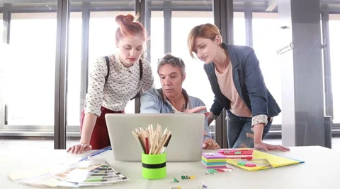 Smiling creative director discussing a new project on laptop with team Stock Footage 59543636