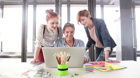 Smiling creative director looking at laptop with his team and discussing plans Stock Footage 59543614