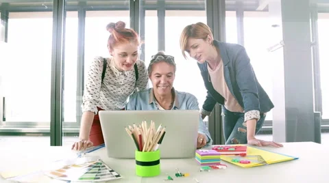 Smiling creative director looking at laptop with his team and discussing plans Stock Footage 59543625