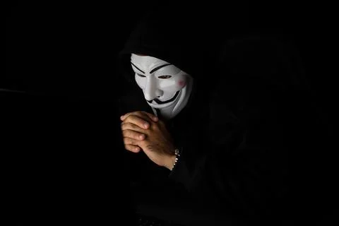 Smiling criminal anonymous mask's hacker trying to approach data. Surmise. 写真素材