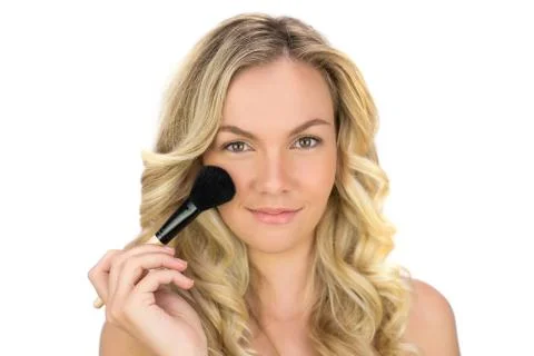 Smiling curly haired blonde using powder brush Stock Photos