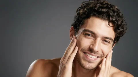 Smiling curly haired man touching his face in studio portrait Stock Footage 338346085