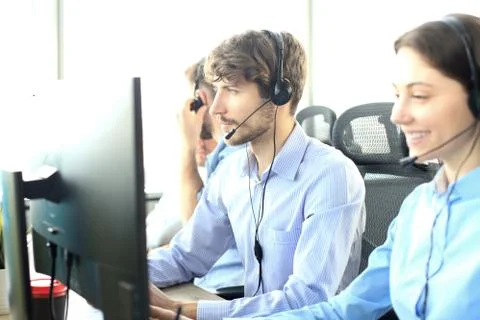Smiling customer support operator at work with team at the background. Stock Photos