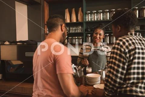 Smiling customers ordering coffee from a cafe barista Stock Photos