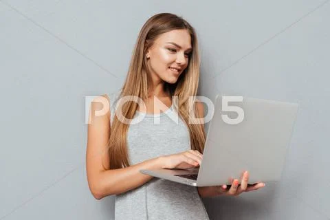 Smiling cute girl standing and using laptop Stock Photos