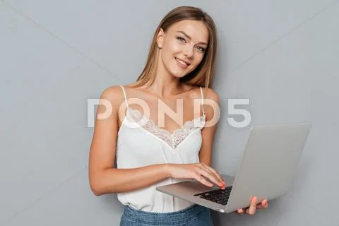 Smiling cute girl using laptop and looking at camera Stock Photos