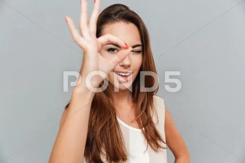 Smiling cute young woman looking through fingers Stock Photos