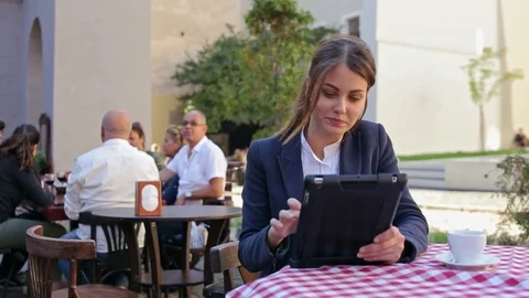 Smiling cute young woman using tablet in terrace of cafe Stock Footage 82406936