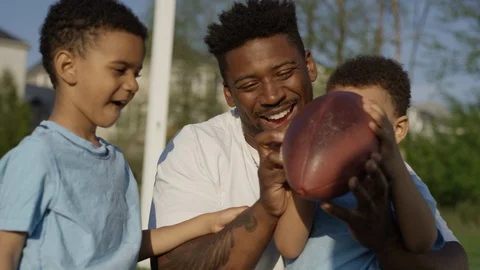 Smiling dad teaching kids to play football Vídeos de archivo 89923802