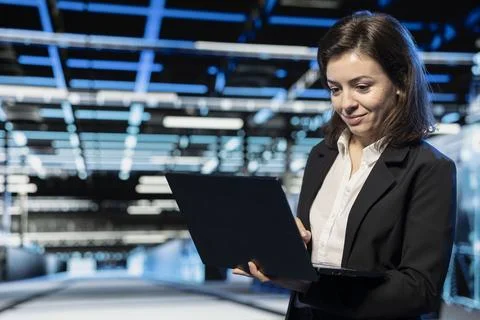 Smiling data center computer scientist using laptop to configure mainframes Stockfoto's
