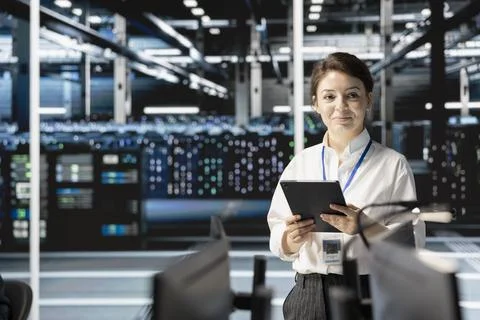 Smiling data center engineer programming diagnostic scripts on tablet Stock Photos