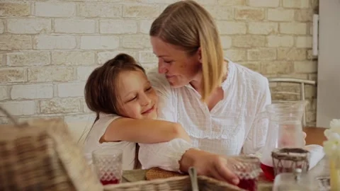 Smiling daughter embracing mother while having food at dining table Video stock 166440169