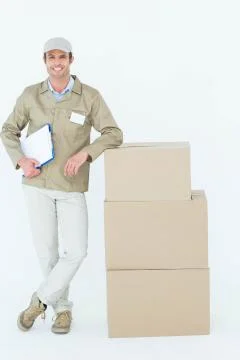 Smiling delivery man standing by stack of boxes 写真素材